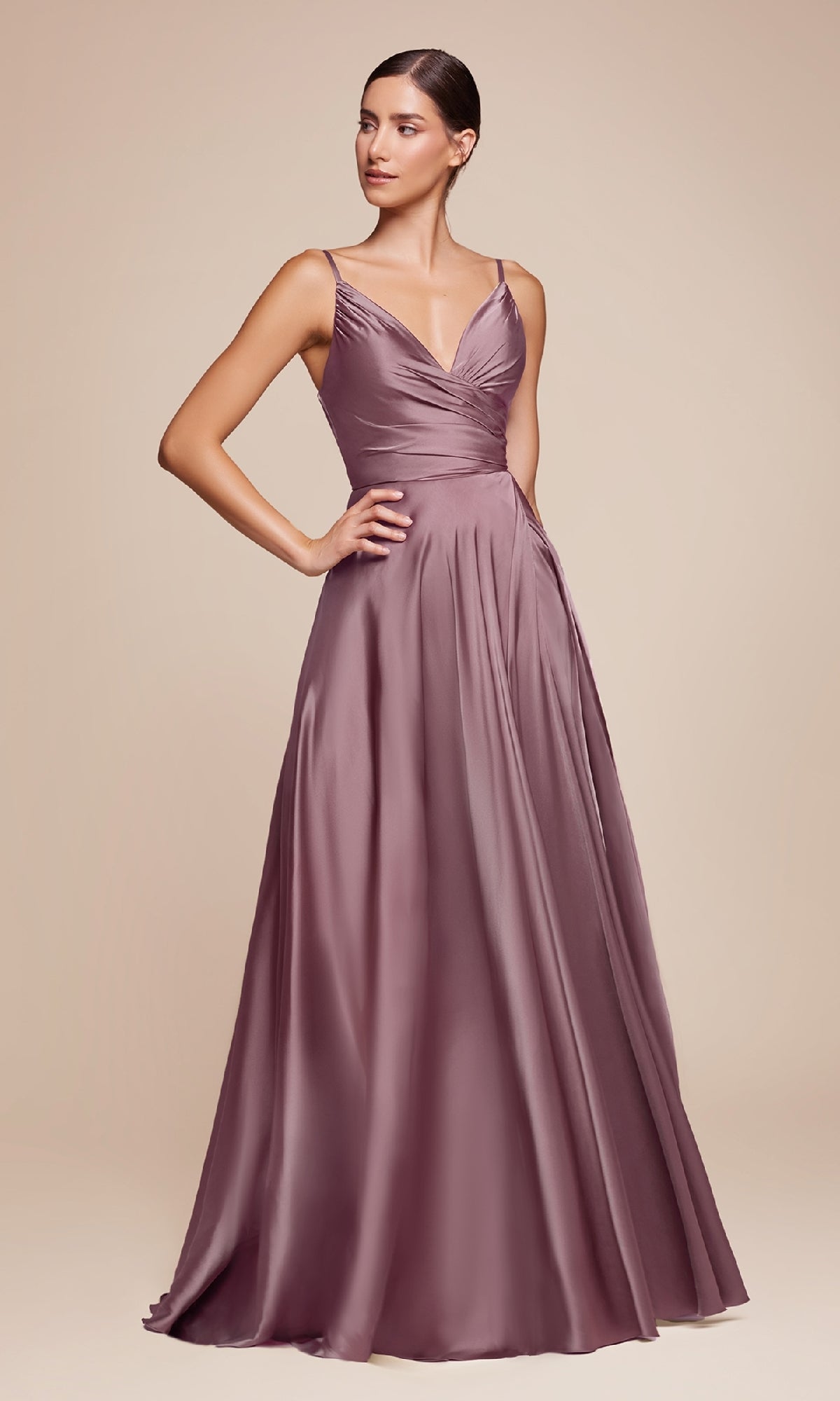 A woman poses in the Ladivine 7485-1 Classic A-Line Satin Prom Dress, featuring a floor-length mauve design with thin straps and a V-neckline, set against a plain beige background.